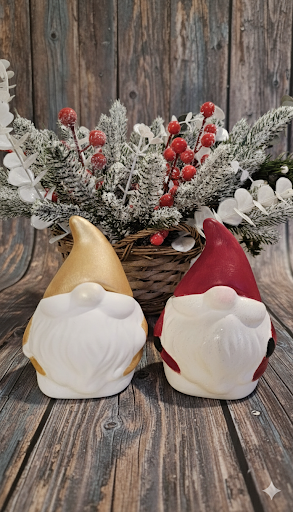 Santa soy candle in gold and red with festive holiday decor and greenery.