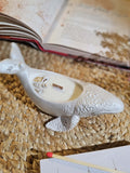 MoonWhale – Handmade Whale Shaped Soy Candle  – Ocean Magic for Your Space resting on a woven mat with an open book in the background.