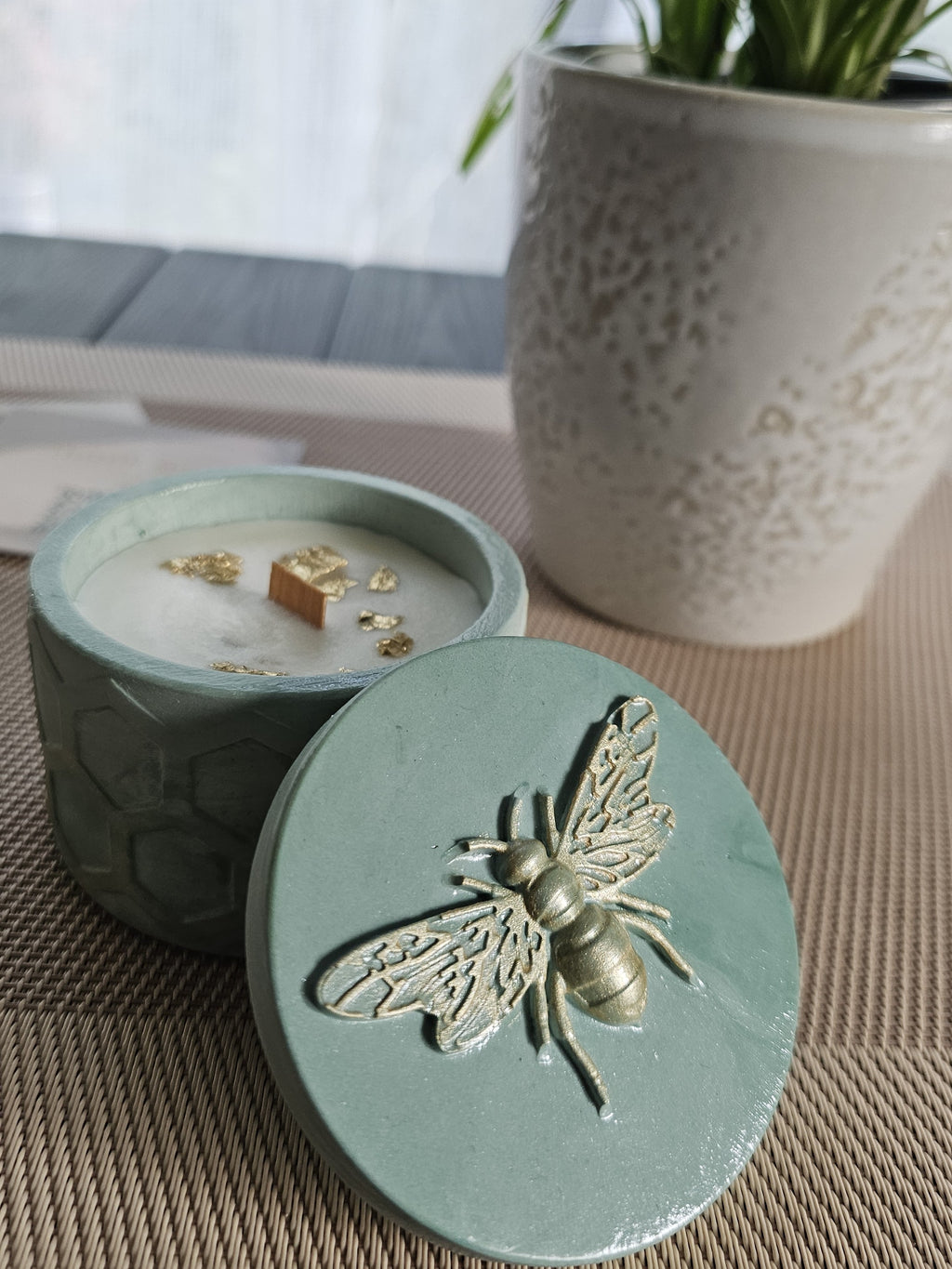 Soy candle with wooden wick in a decorative green container featuring a bee design, showcasing a blend of Tobacco & Sweet Honey.