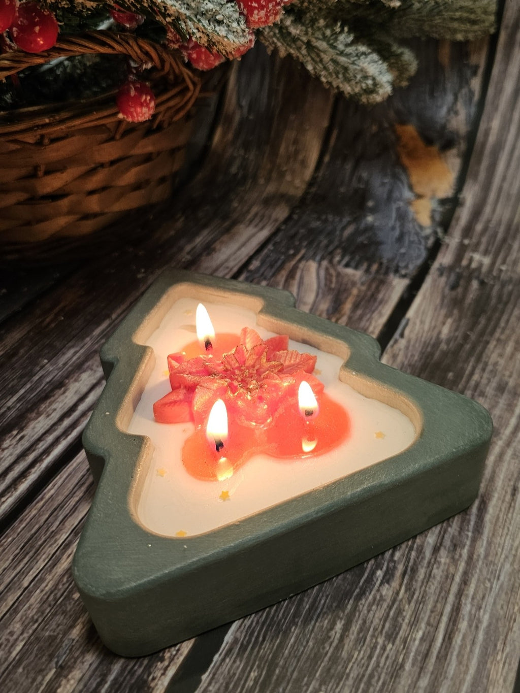 Christmas tree candle in green handmade gypsum form, decorated with star accents and poinsettia details.