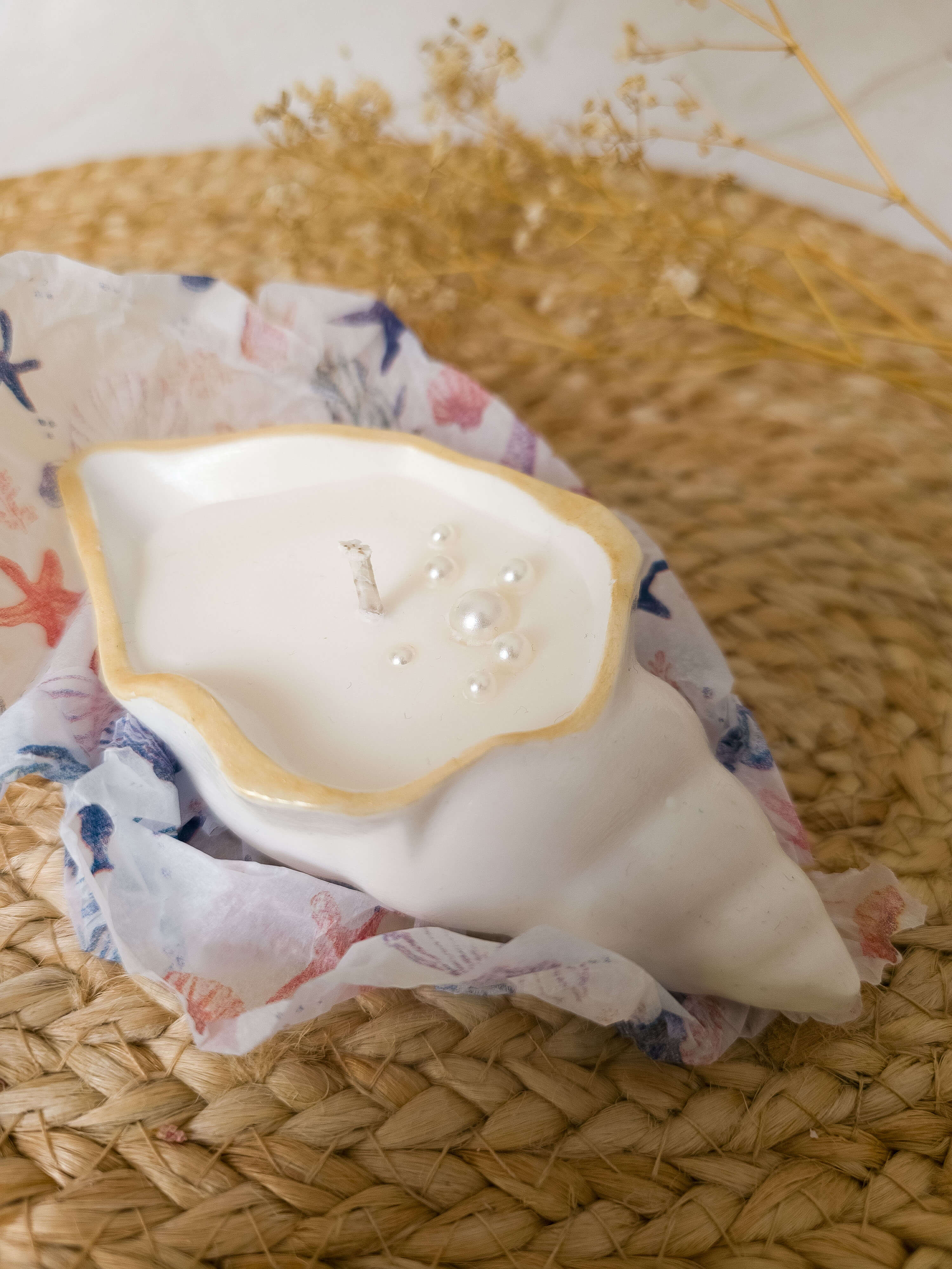Seashell Gift Set candle by Mellow Flame on floral cloth, showcasing ocean-inspired design with pearl accents.